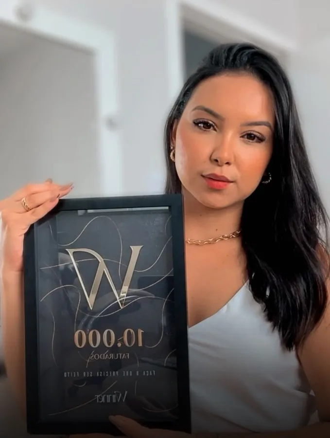 Aluna Winner segurando a placa de 10 mil faturados