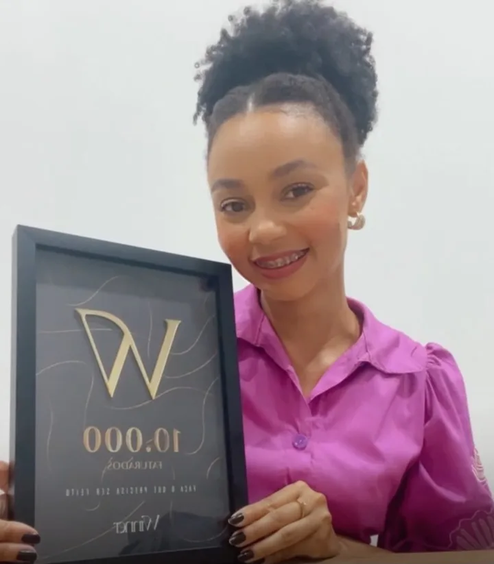 Aluna Winner sorrindo com a placa de 10 mil faturados